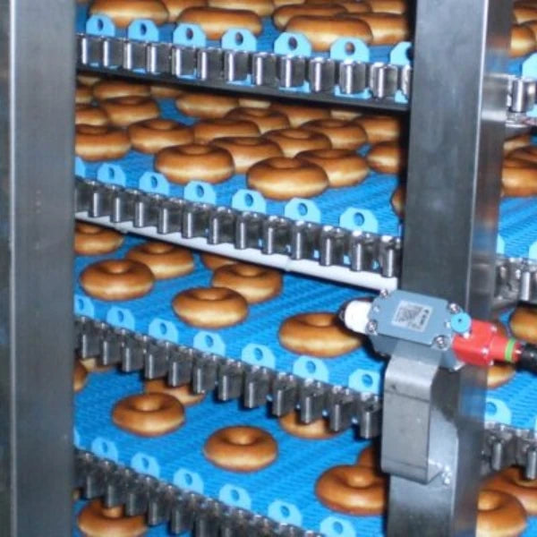 close up of donuts on the conveyor of an industrial forced air cooling system
