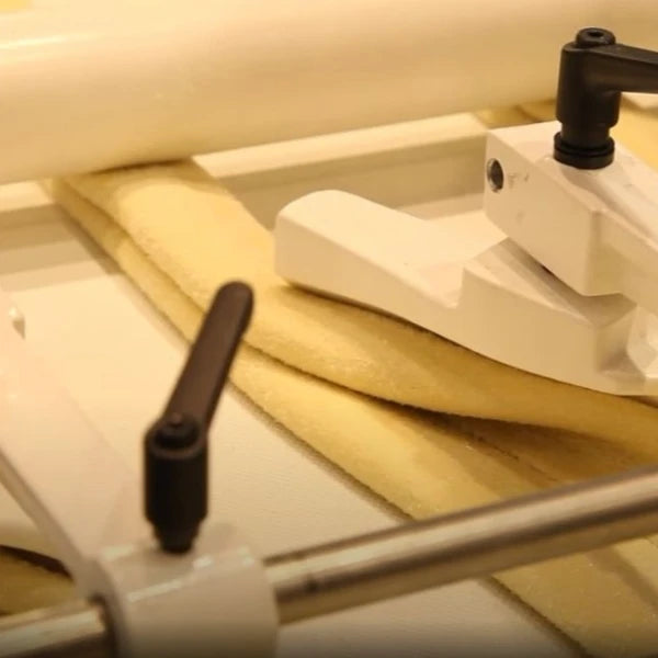 Close-up of a croissants being rolled and moulded inside of the wholesale pastry line.