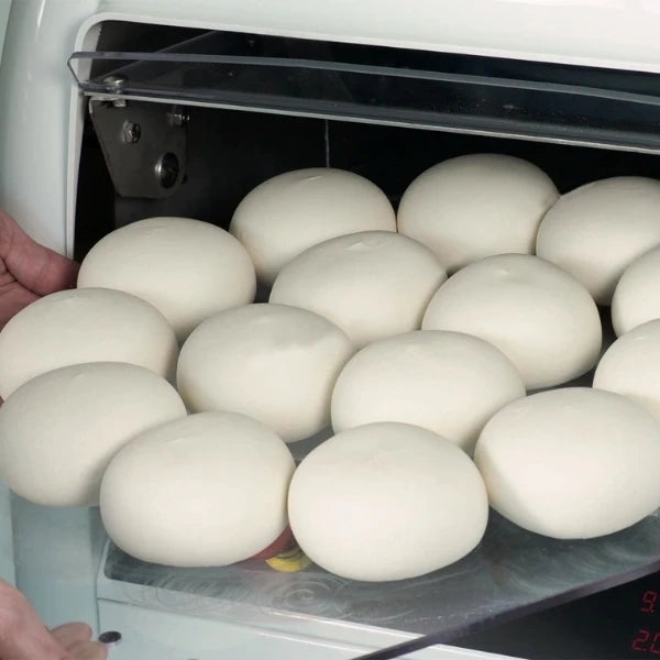 A close-up of dough balls coming out of the Empire SPA Dough Divider and Rounder